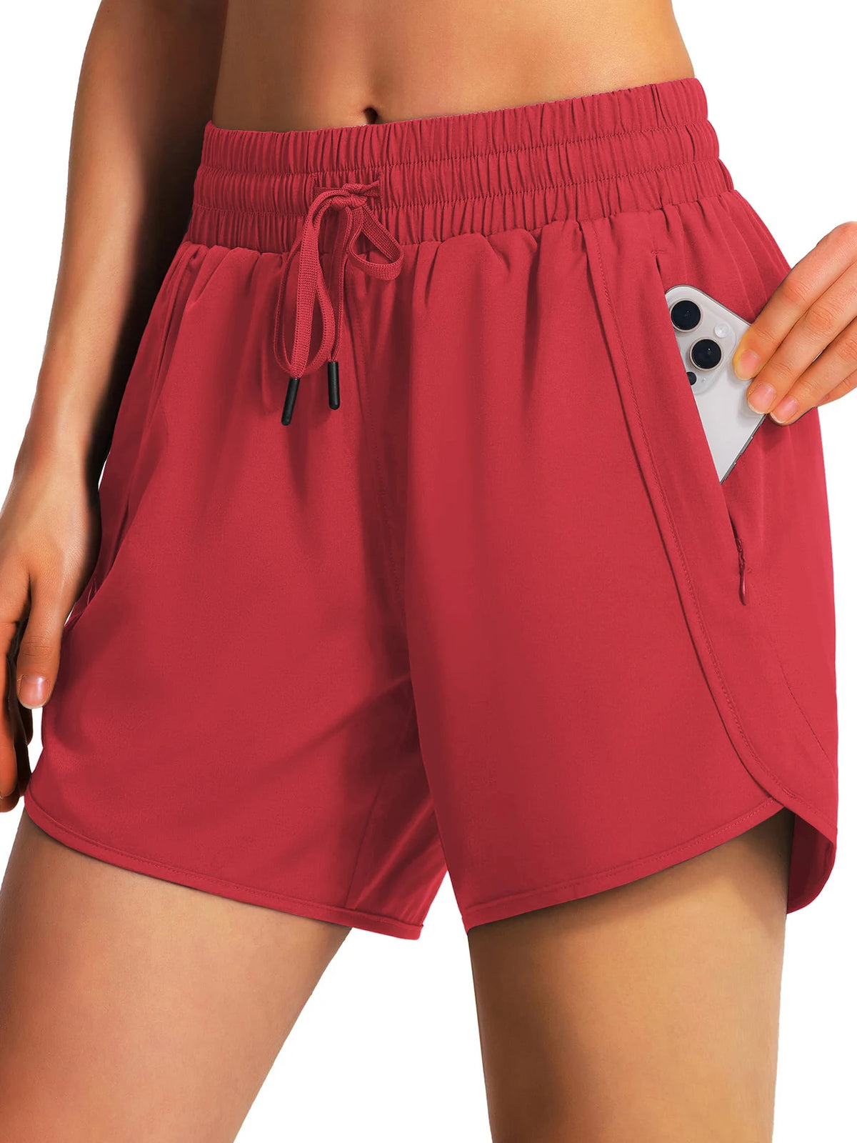 A woman wearing coral red quick-dry sports running shorts with an adjustable drawstring and side pockets.