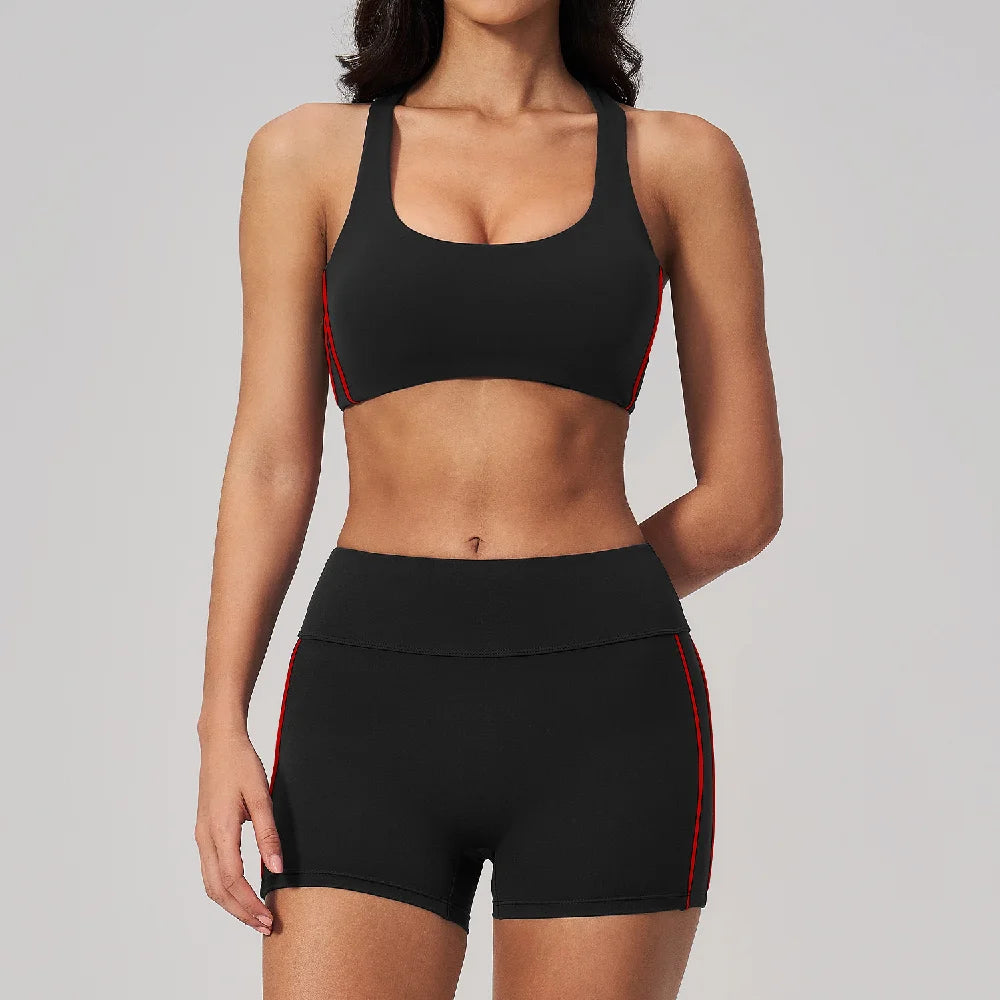 A woman wearing a black two-piece yoga and sports tracksuit set with red trim.