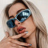 Close-up of a woman wearing blue Y2K retro sports sunglasses with light blonde hair.
