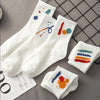 A stack of white breathable cotton socks featuring colorful abstract patterns on a gray background.