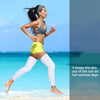 A woman running outdoors wearing UV protection compression leg sleeves and a sports bra on a sunny beach.