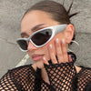 Close-up of a woman wearing silver Y2K retro sports sunglasses against a gray background.