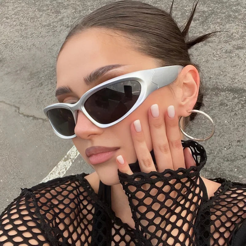 Close-up of a woman wearing silver Y2K retro sports sunglasses against a gray background.