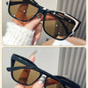 Black khaki/tea vintage square cat eye sunglasses being held by a hand