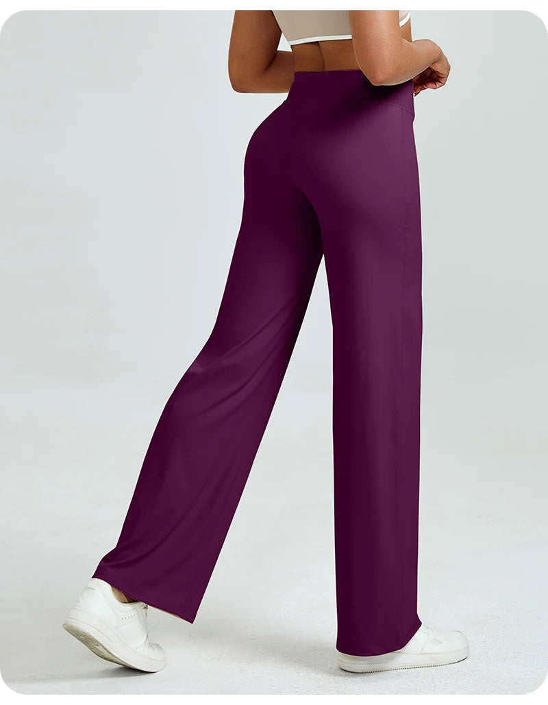 A woman is modeling high waisted purple yoga pants with a white top and white sneakers.