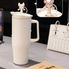 A white insulated thermos mug with a lid and handle is shown next to a calendar and a book.