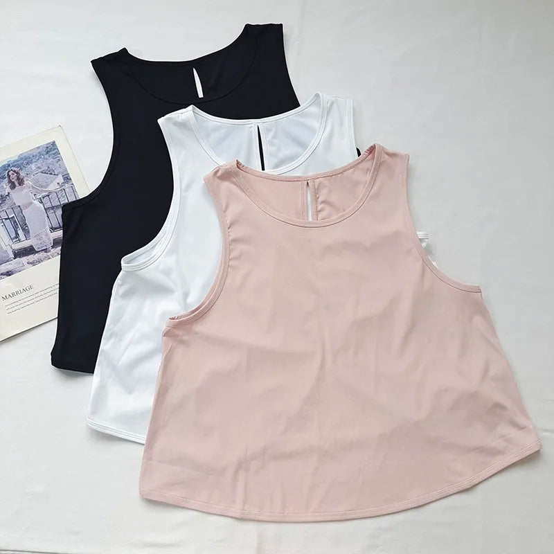 Ein Set aus drei nahtlosen Sport-Tanktops in Schwarz, Weiß und Pink für Yoga und Fitness.