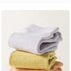 Une pile de chaussettes de yoga et de sport en tricot doux dans les tons violet clair, jaune pâle et pêche.