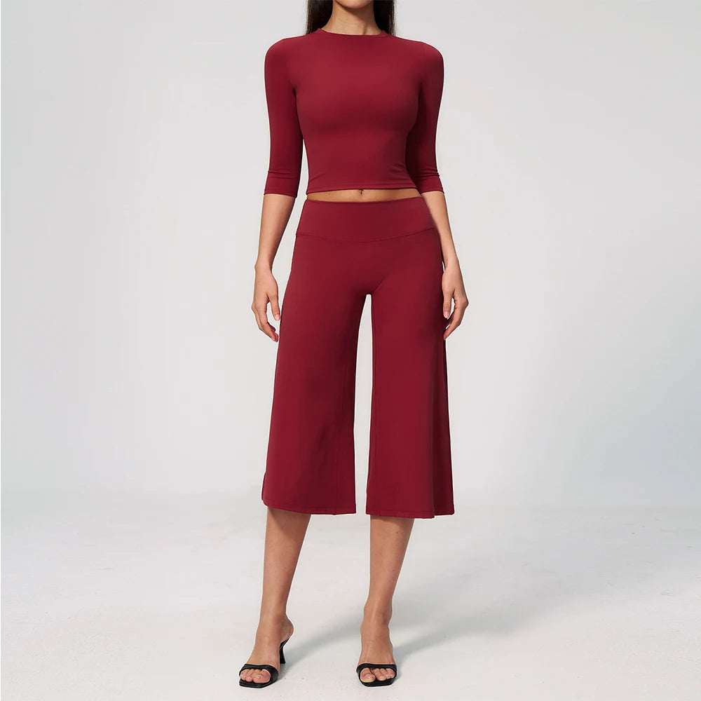A woman wearing a maroon yoga and fitness leggings set consisting of a long-sleeved top and matching pants.