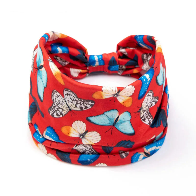 A red fabric headband featuring a floral butterfly pattern in blue, orange, and white.