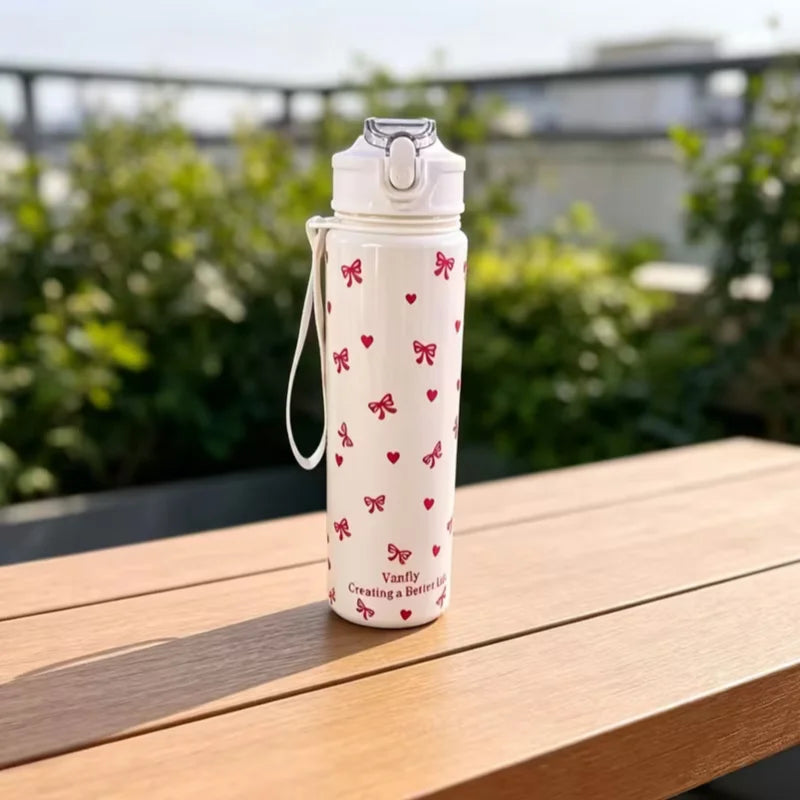 A white tumbler with a floral pattern sits on a wooden table outdoors.