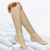 A pair of beige medical grade compression socks being worn on a foot against a white background.
