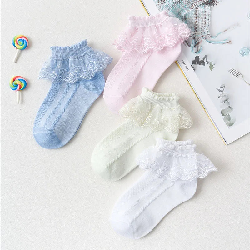 Collection de chaussettes à volants en dentelle roses, bleu clair et blanc pour filles, présentées sur une surface blanche.