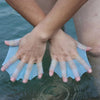 Hands wearing silicone swim training flippers dipping into water.
