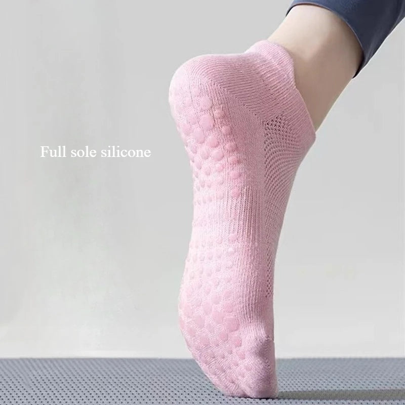 Chaussettes de yoga et de fitness roses respirantes portées sur un pied contre une surface grise.