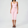 A woman wearing a pink women's premium fitness tracksuit consisting of a cropped tank top and matching leggings.