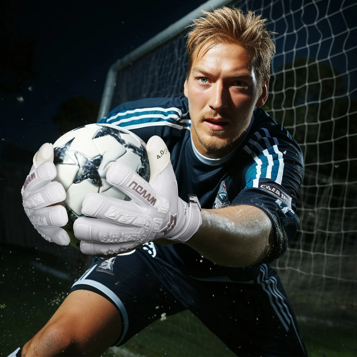 A male soccer goalkeeper wearing dark blue uniform and white gloves is positioned in front of a net.