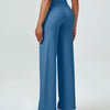 A woman is modeling high waisted blue yoga pants in a full-length shot.