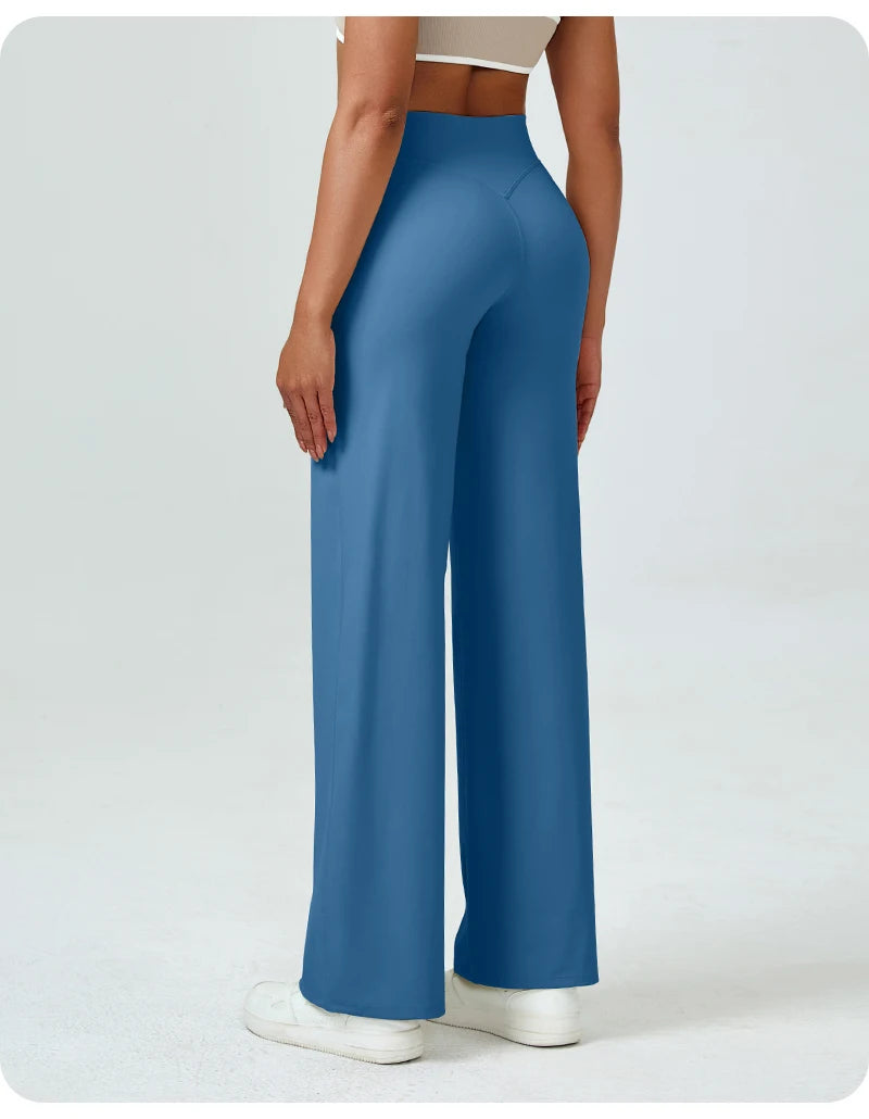A woman is modeling high waisted blue yoga pants in a full-length shot.