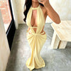 A model wearing a yellow elegant maxi dress with a draped cut-out back, standing in a bright room.
