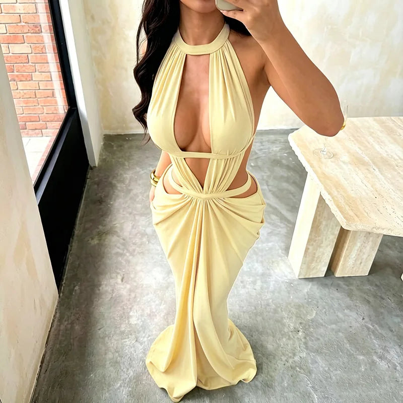 A model wearing a yellow elegant maxi dress with a draped cut-out back, standing in a bright room.