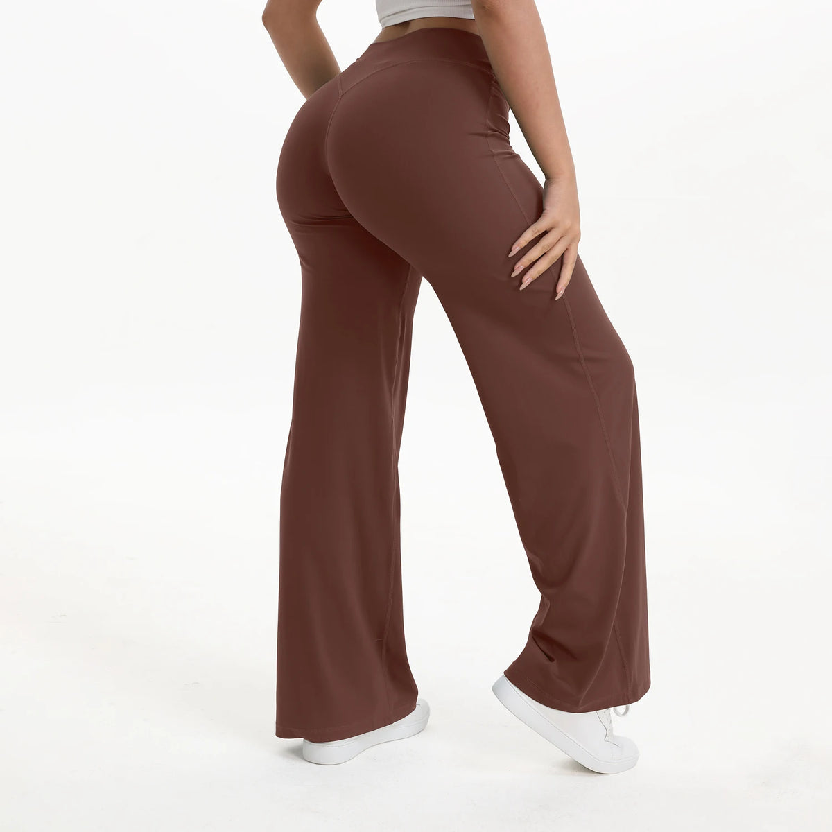 A person is modeling brown NCLAGEN SoftMotion straight leg yoga pants in a full-length shot.