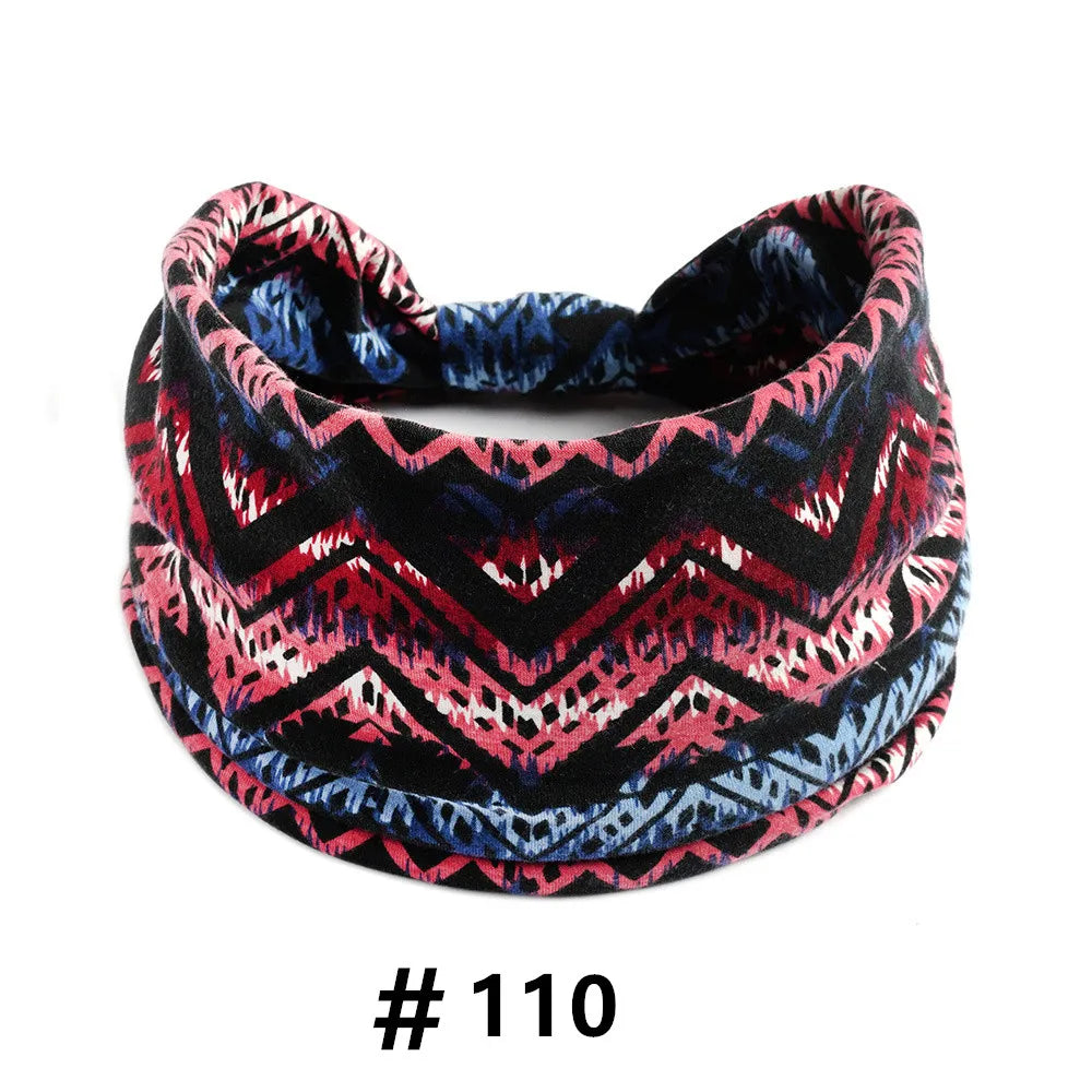A black patterned boho cotton turban headband with pink, red, and blue geometric designs.
