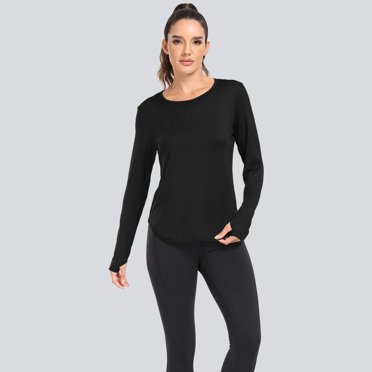 A woman models a black loose fit sun protection t-shirt and black leggings.