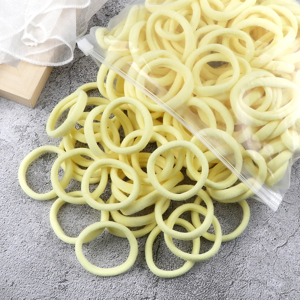 A pile of light yellow elastic hair bands is displayed on a gray surface.