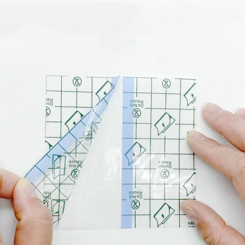 A hand holds a transparent sheet of invisible leg lifting patches with a grid pattern on a white surface.