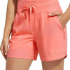 A model is wearing coral pink high-waisted quick-dry athletic shorts with a drawstring waist.