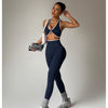 Eine Frau modelliert ein marineblaues Sport-BH und passende nahtlose Leggings mit weißer Borte in einem Studio.