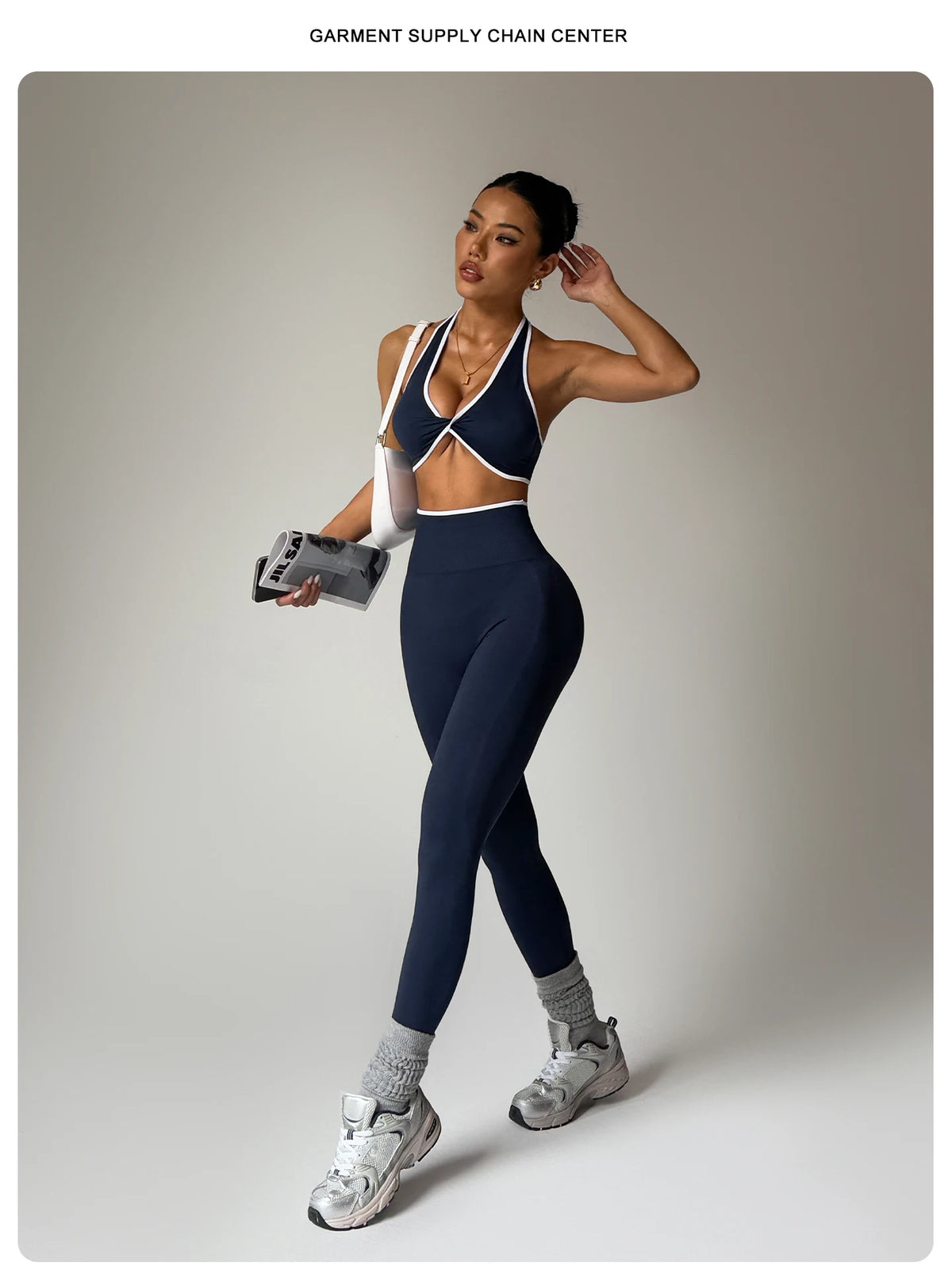 Eine Frau modelliert ein marineblaues Sport-BH und passende nahtlose Leggings mit weißer Borte in einem Studio.