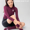A woman models a long-sleeved maroon athletic top and black leggings while wearing Rockbros Road to Sky cycling socks.