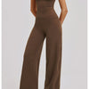 A woman models a brown women's premium fitness tracksuit in a fitted, long-sleeved top and matching trousers.