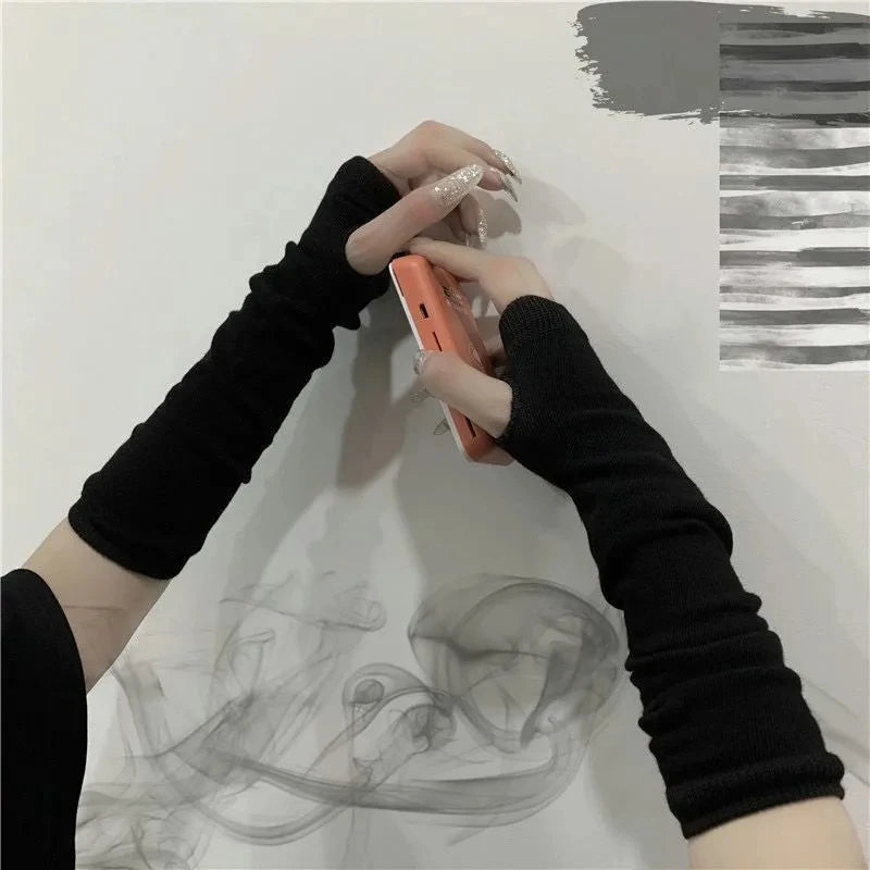 Eine Person mit schwarzen Finger-Armwärmern hält ein orange Smartphone vor weißem Hintergrund.