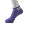 Purple non-slip grip socks with white stripes on a model's foot.