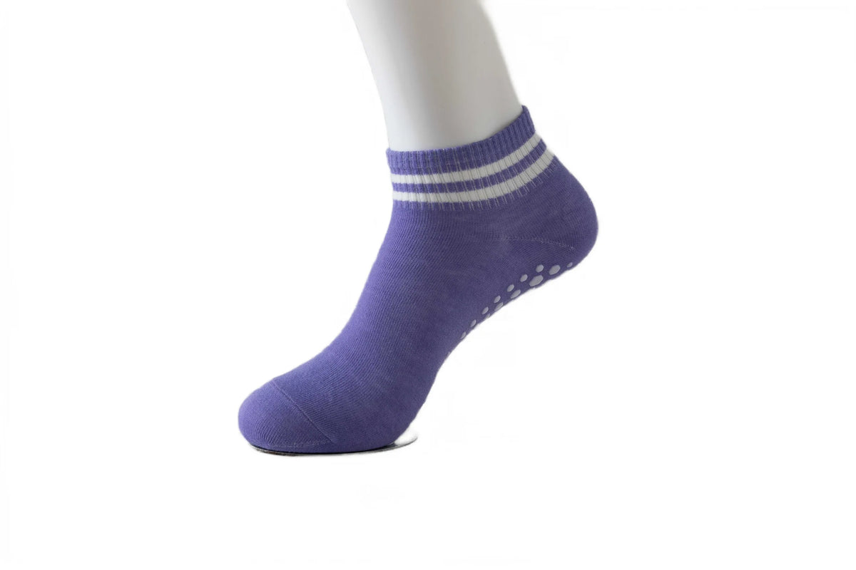 Purple non-slip grip socks with white stripes on a model's foot.