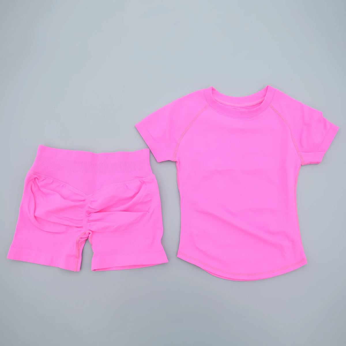 Ensemble de yoga et fitness rose vif, sans couture, pour femmes, composé d'un haut à manches courtes et de shorts assortis.