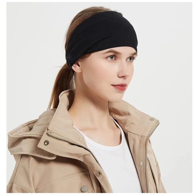 A woman wearing a black stretch sports headband and a beige jacket.
