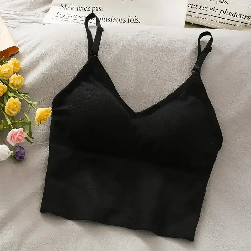 Black off-shoulder camisole tank top laid on a white surface next to yellow roses.