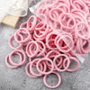 A pile of pink elastic hair bands in various sizes and colors packaged in a clear plastic bag