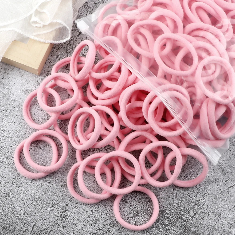 A pile of pink elastic hair bands in various sizes and colors packaged in a clear plastic bag
