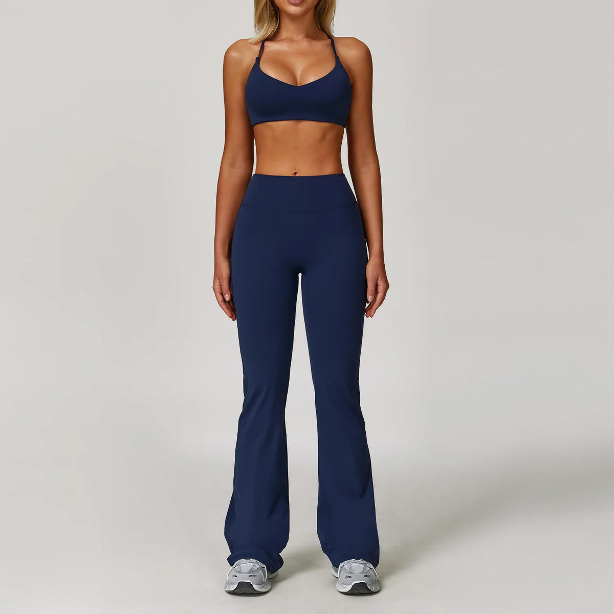 A woman models a navy blue 3-piece yoga sports set consisting of a cropped top and full-length leggings.