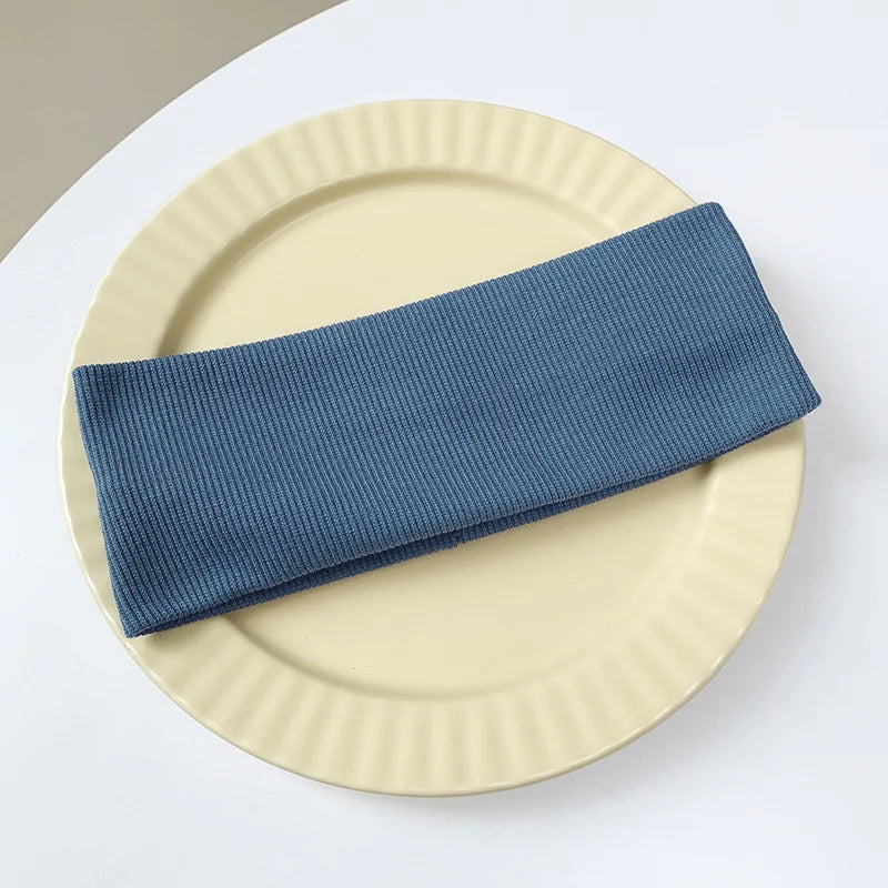 A navy blue elastic hairband is placed on a light beige plate.