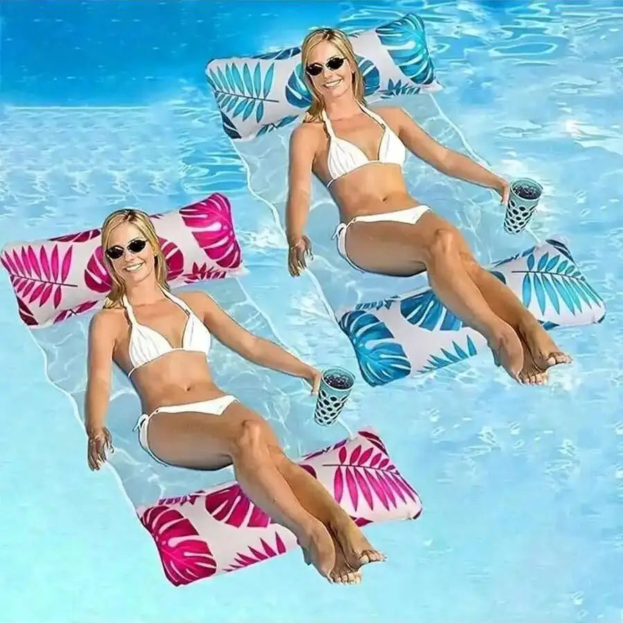 A woman wearing a white bikini floats on a blue pool with pink and teal inflatable pillows.