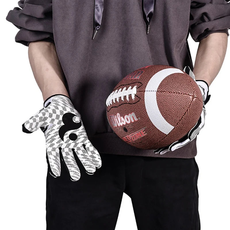 Une personne en chemise sombre tient un ballon de rugby marron et blanc et une paire de gants de sport blancs.