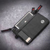 A black slim wallet with a clear card slot and RFID blocking features is shown on a gray surface.