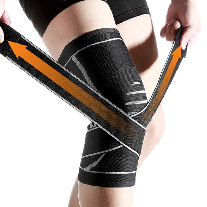 Black adjustable sports knee pads with orange directional arrows wrapped around a person's leg.