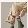 A close-up of a person wearing beige trousers and olive green striped socks.